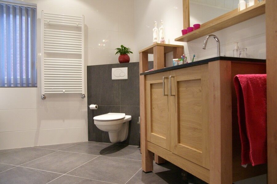 Opgeleverde badkamer met wastafelmeubel en designradiator