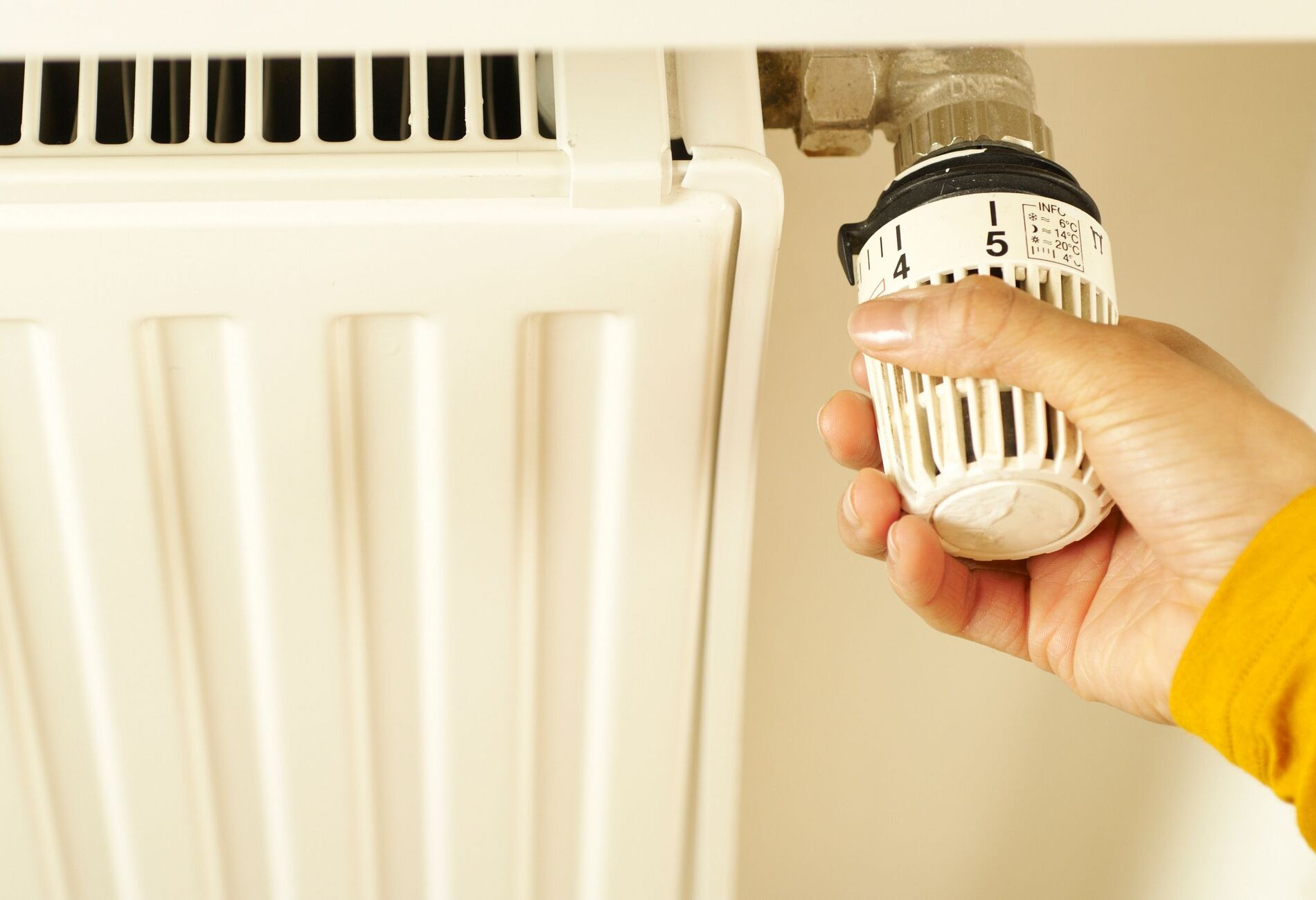 Hand aan de thermostaatknop van een radiator